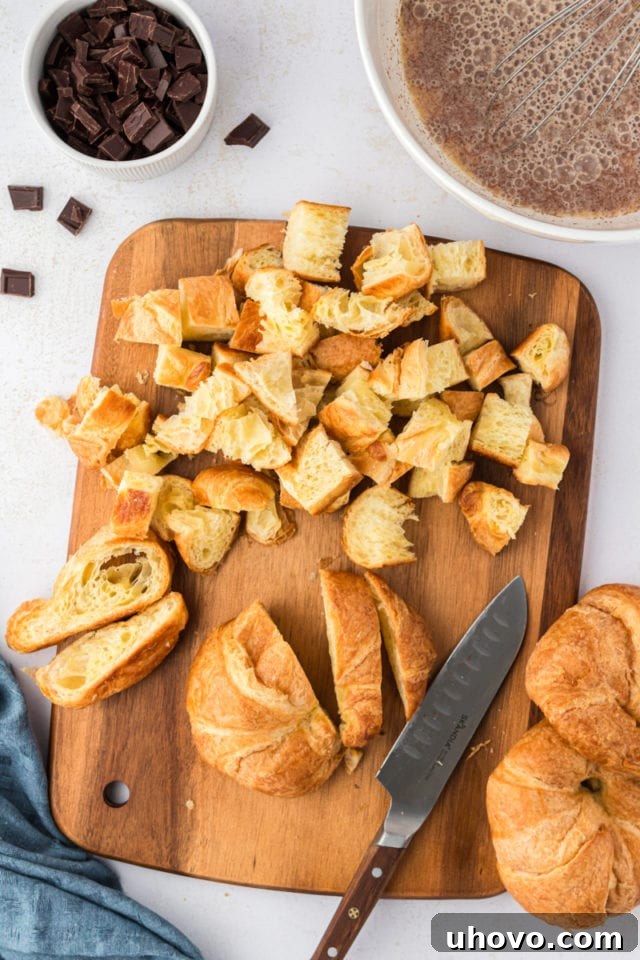 Overhead view of croissants being cut into uniform cubes on a cutting board