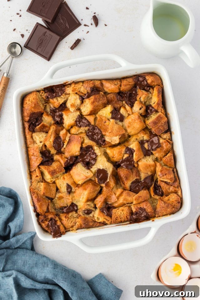 Overhead view of baked chocolate croissant bread pudding in a white square baking dish, golden brown