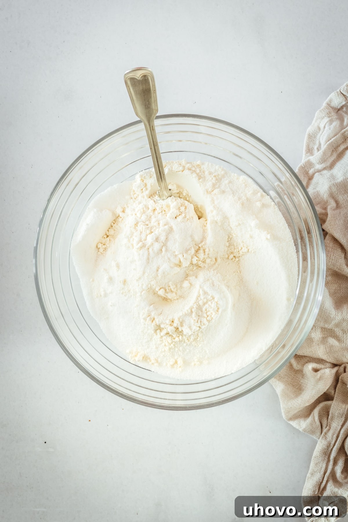 Overhead view of the dry muffin ingredients (flour, sugar, baking powder, salt) whisked together in a glass bowl.