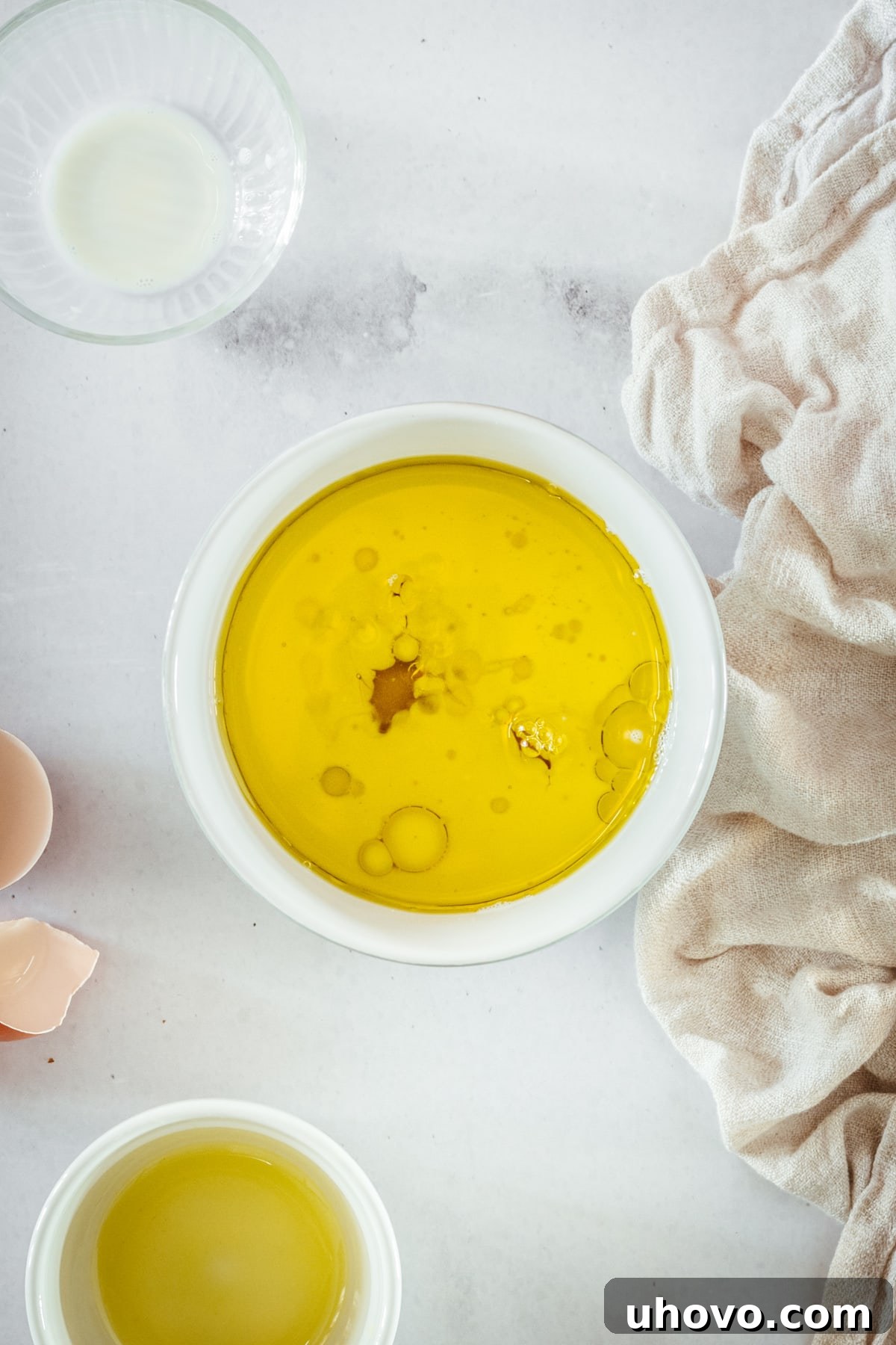 Overhead view of the wet muffin ingredients (milk, oil, eggs) being combined in a bowl.