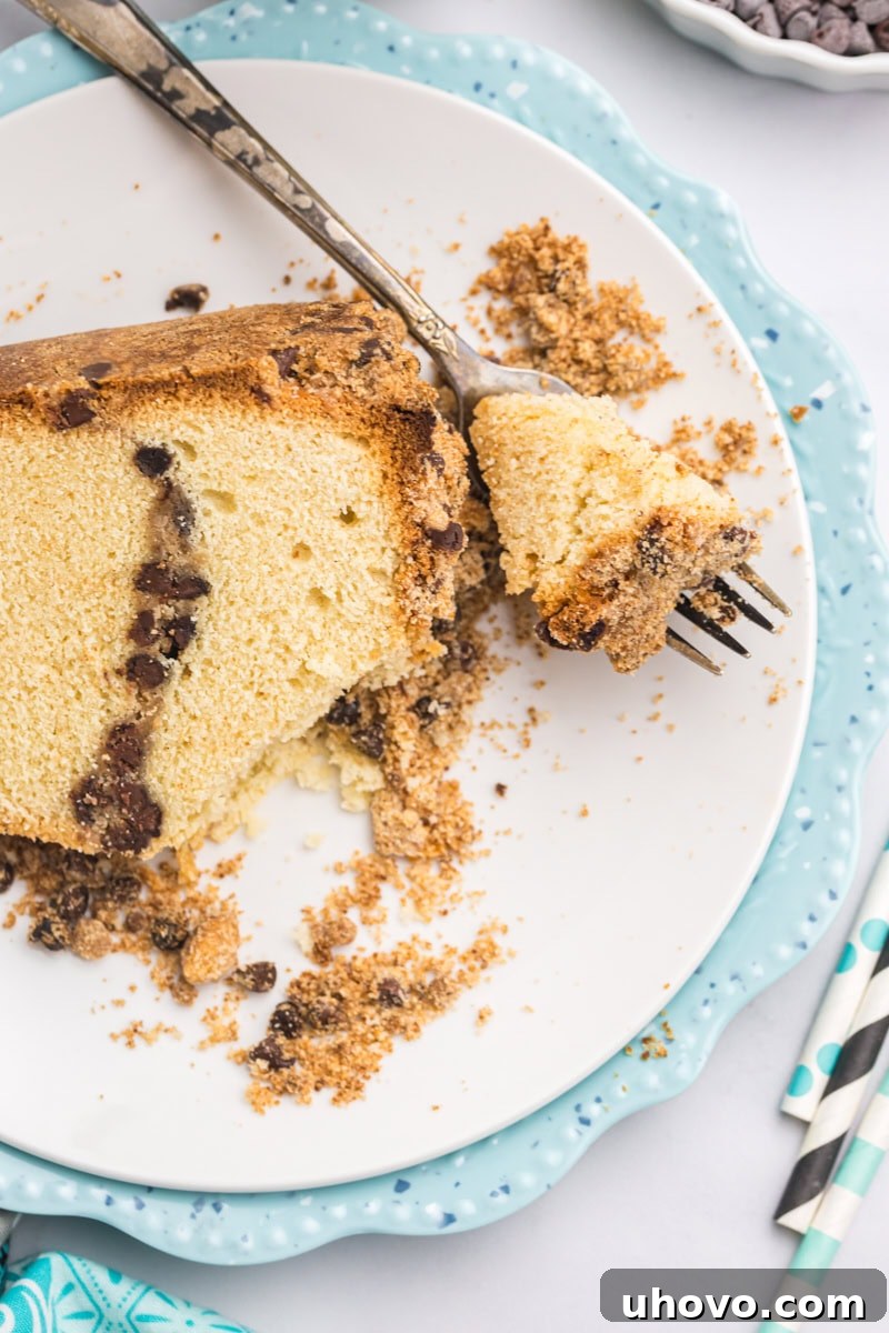An inviting overhead view of a slice of chocolate chip crumb pound cake on a pristine plate, with a bite playfully poised on a fork, ready for tasting.