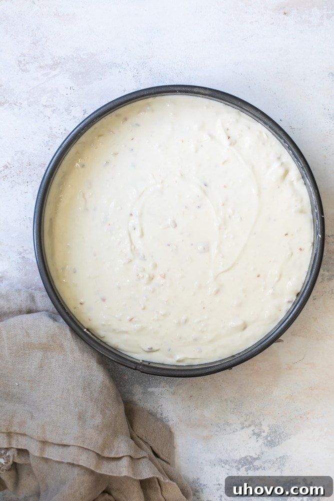 A springform pan filled with the creamy, light-colored Chocolate Coconut Almond Cheesecake batter, ready for baking.