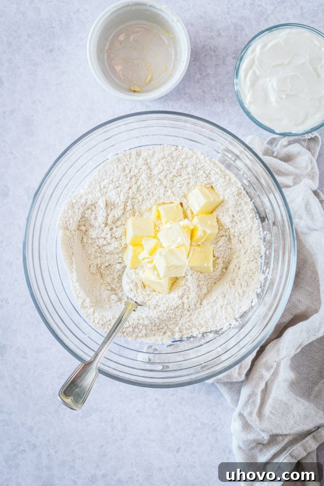Overhead view of cold, cubed butter added to the dry ingredients in a glass mixing bowl, ready to be cut in.