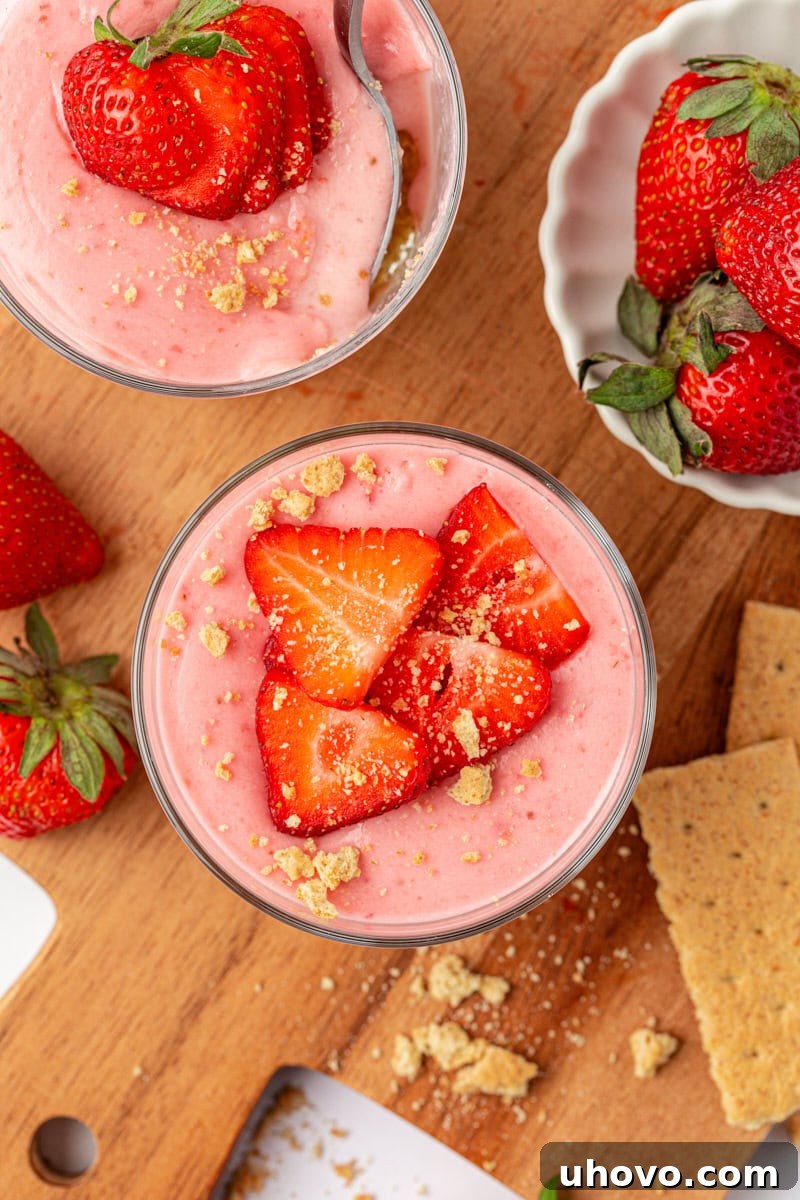 An inviting overhead view of two strawberry no-bake cheesecakes, artfully garnished with fresh strawberry slices and a sprinkle of graham cracker crumbs, ready to be enjoyed.