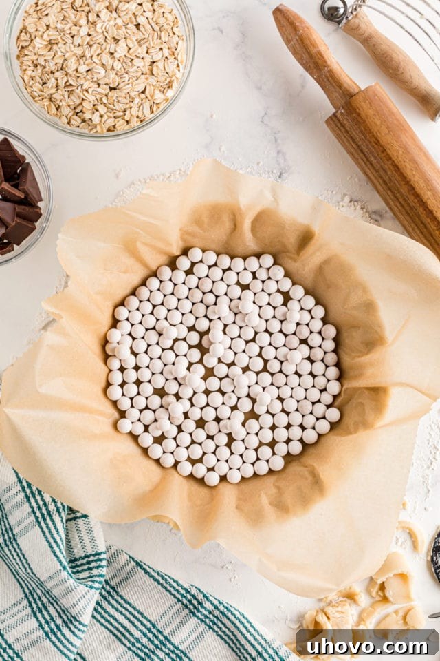 Parchment paper lining a pie crust and filled with pie weights for par-baking.