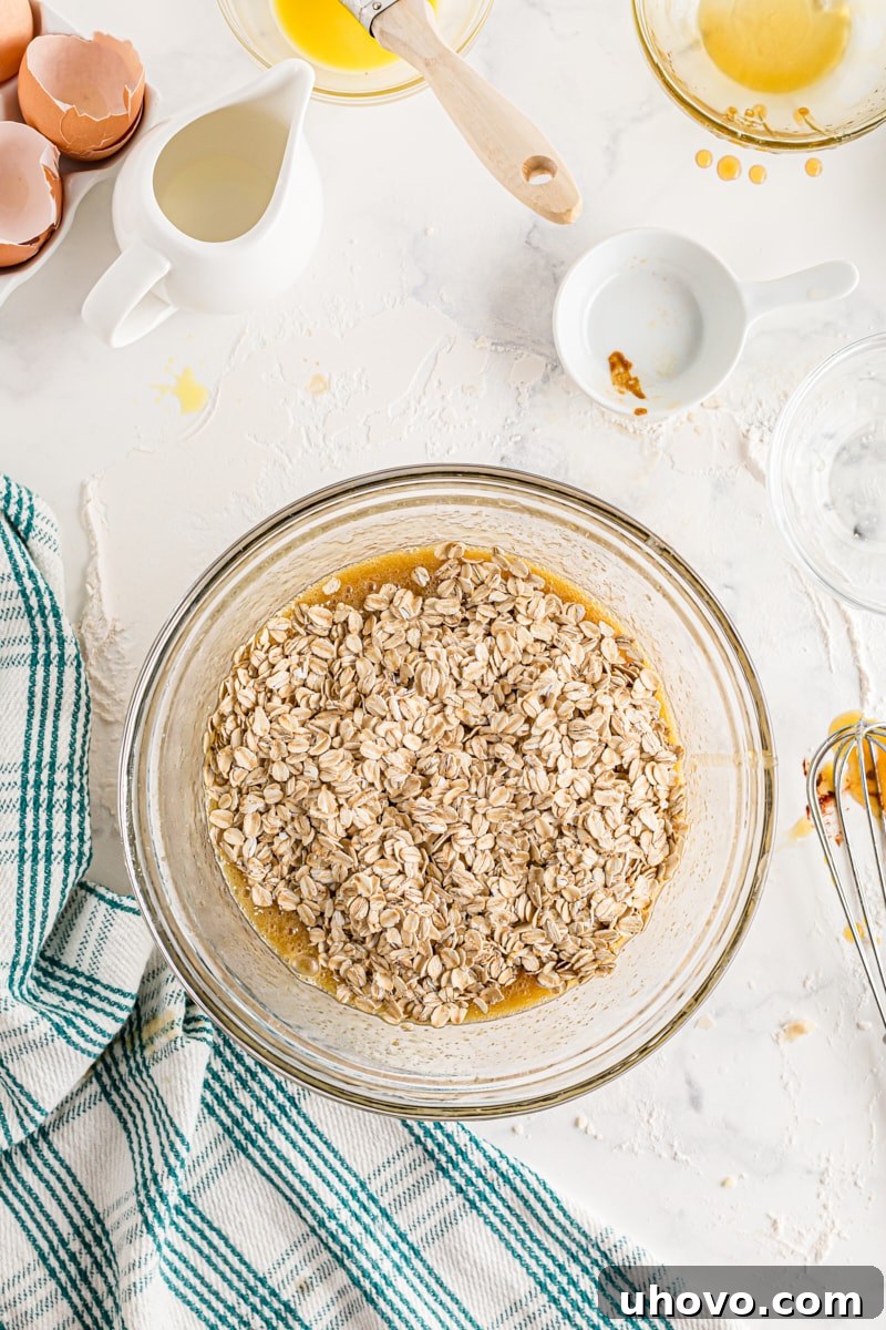 Toasted old-fashioned oats being stirred into the brown sugar and butter pie filling mixture.