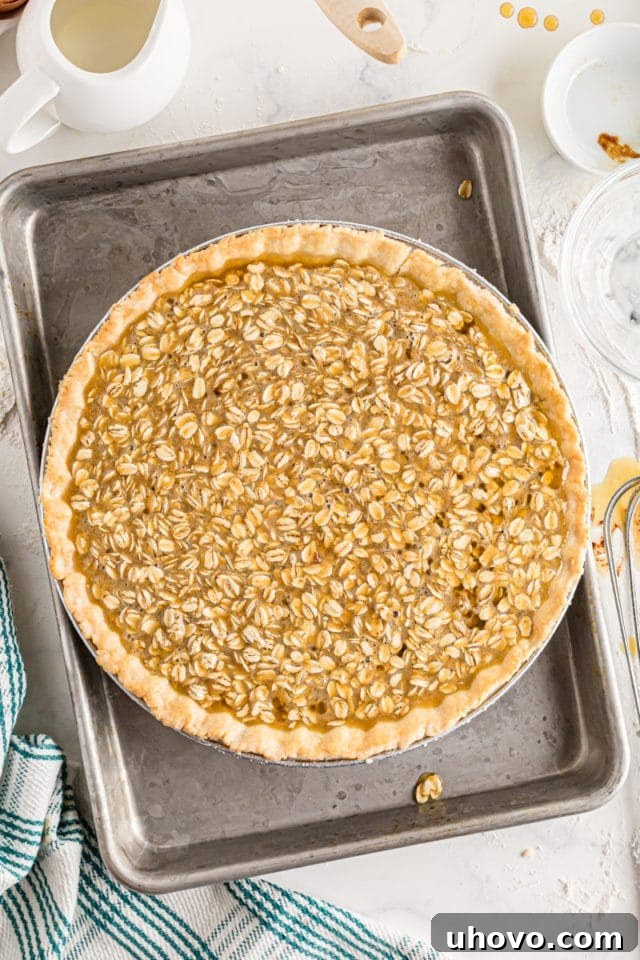 A pie crust generously filled with the gooey oatmeal filling, concealing the chocolate ganache layer below, ready for baking.