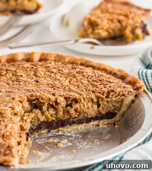 A black bottom oatmeal pie with two slices removed, showing the rich chocolate layer. Slices are visible on plates in the background.