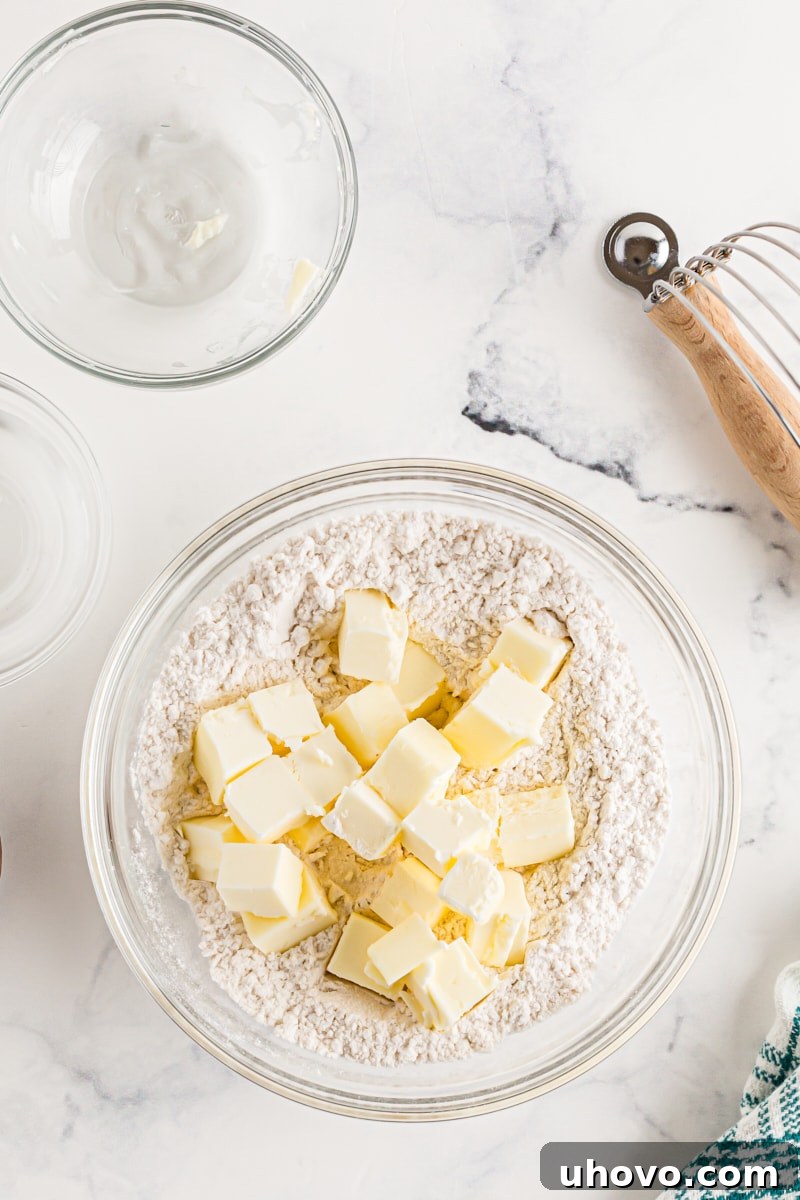 Cold, diced butter cubes scattered over flour in a mixing bowl, ready to be cut in.
