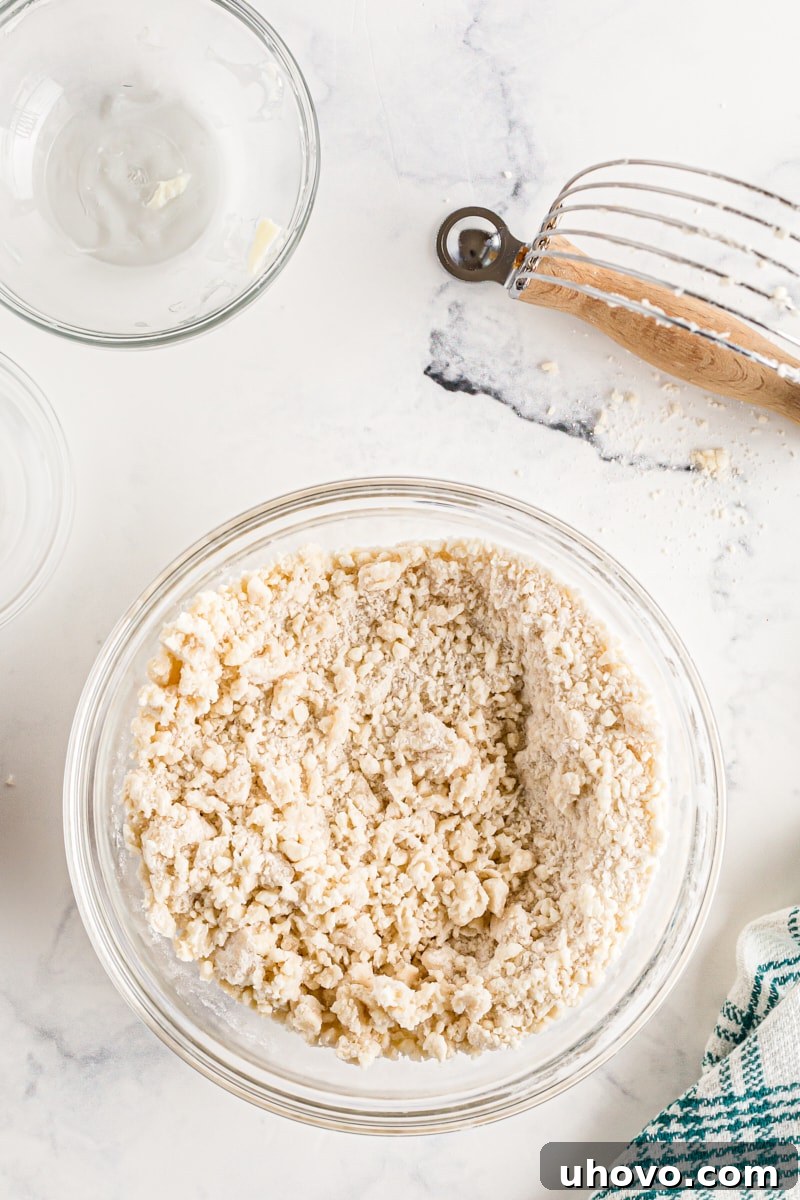 Butter and flour loosely combined in a bowl, forming pea-sized clumps, indicating proper cutting-in technique.