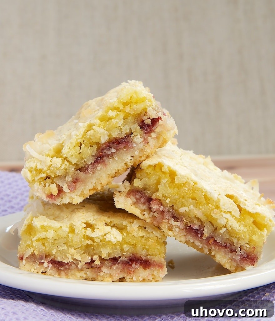 Delicious Coconut Raspberry Bars with three distinct layers: shortbread crust, raspberry jam, and coconut topping.