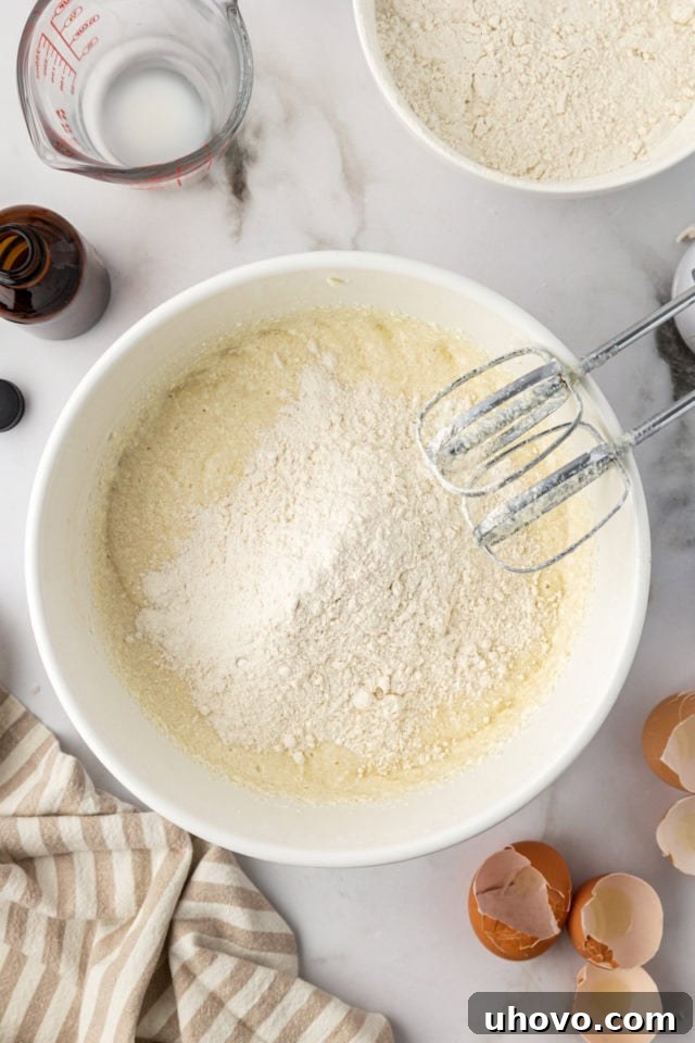 Dry ingredients (flour mixture) being added to the wet cake batter in a mixing bowl