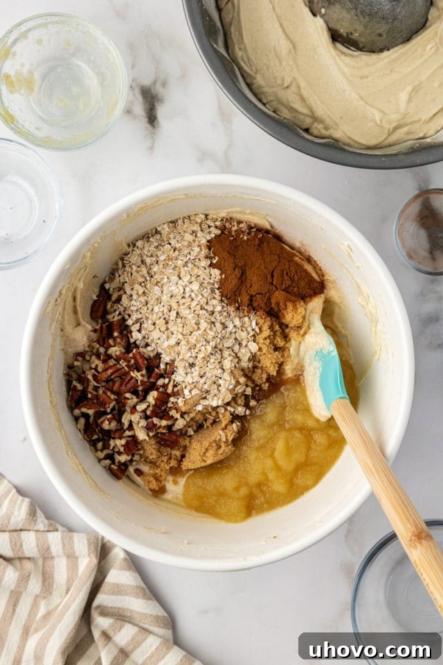 Cinnamon, oats, and nuts being added to the remaining cake batter in a bowl