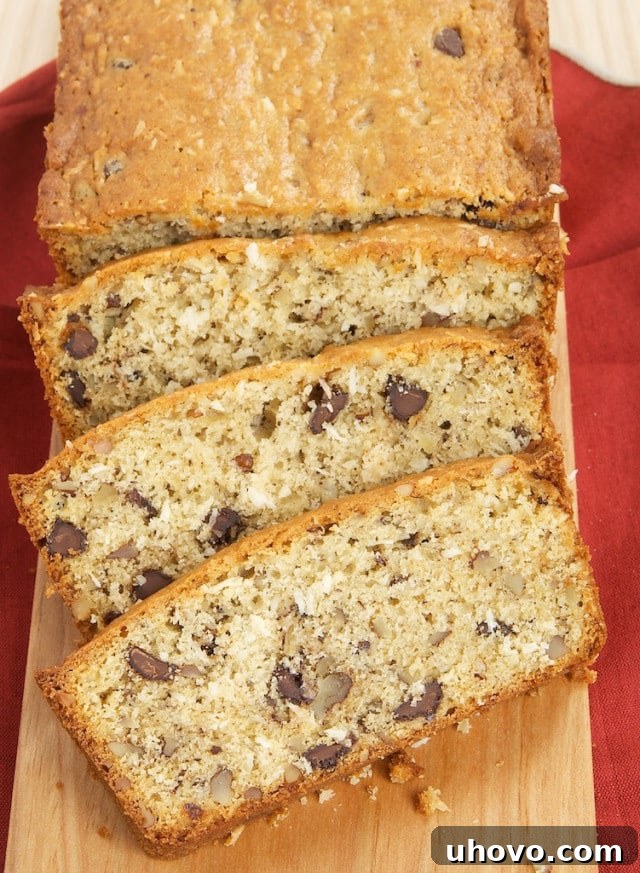Overhead view of a freshly baked Chocolate, Coconut, and Pecan Quick Bread on a rustic wooden serving board, ready to be sliced and enjoyed.