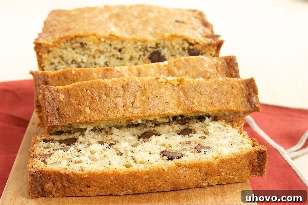 A delicious slice of Chocolate, Coconut, and Pecan Bread packed with chocolate chips, shredded coconut, and chopped pecans, promising a rich texture and delightful flavor.