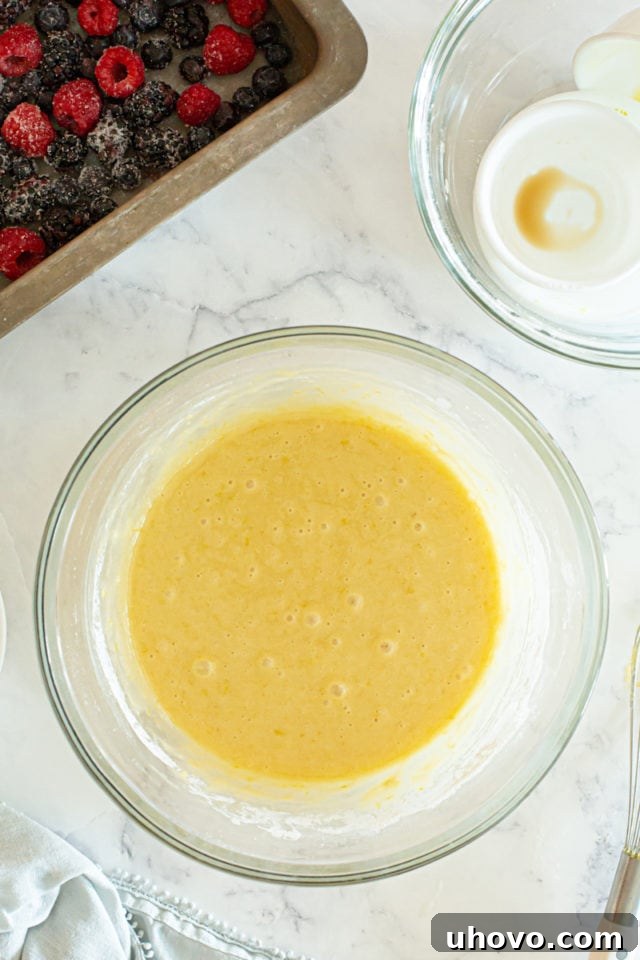 The completed berry pudding cake batter, now smooth and perfectly combined in the glass mixing bowl, ready for baking.