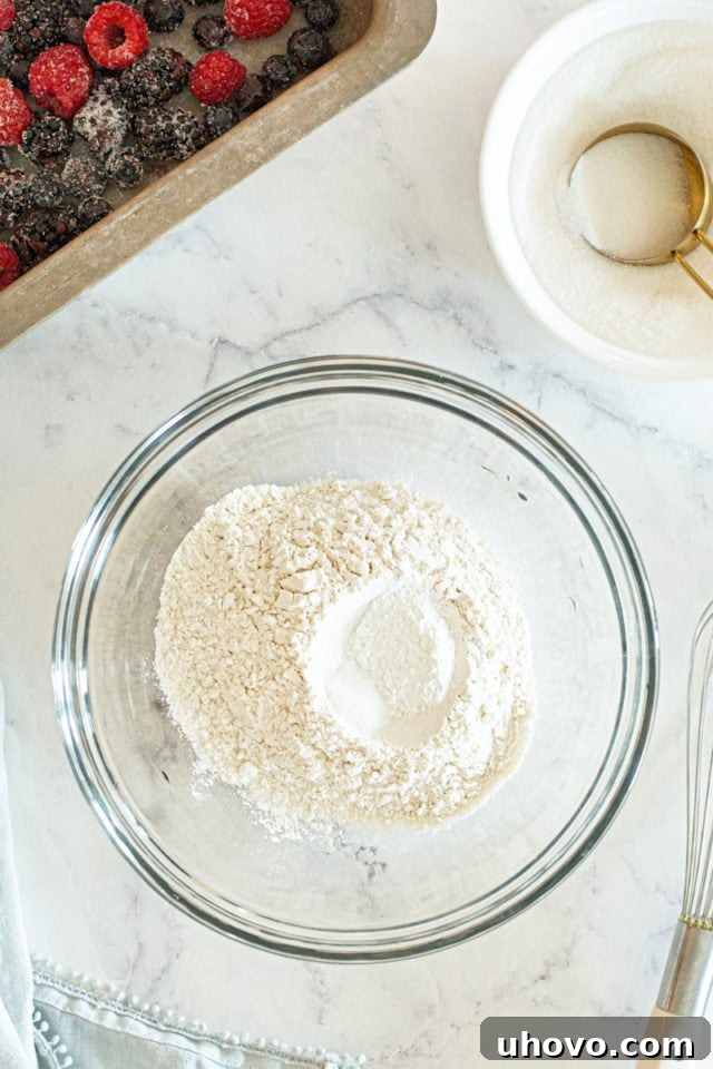 Overhead perspective of a mixing bowl containing the dry ingredients—flour, baking powder, and salt—before they are combined, showing their distinct forms.