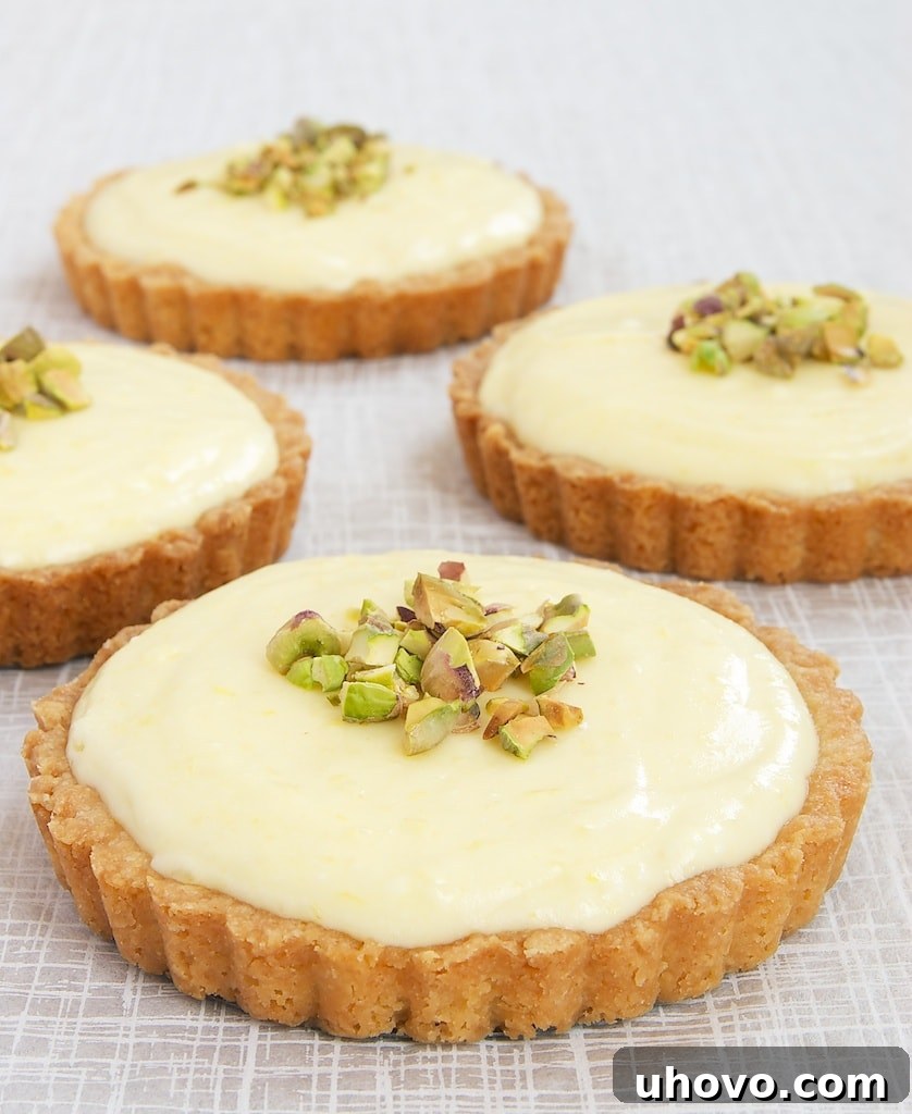 Individual Lemon Cream Tarts arranged beautifully on a white surface