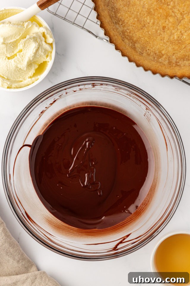 Smooth, melted dark chocolate in a clear glass bowl, cooled to room temperature, ready to be combined with other filling ingredients.