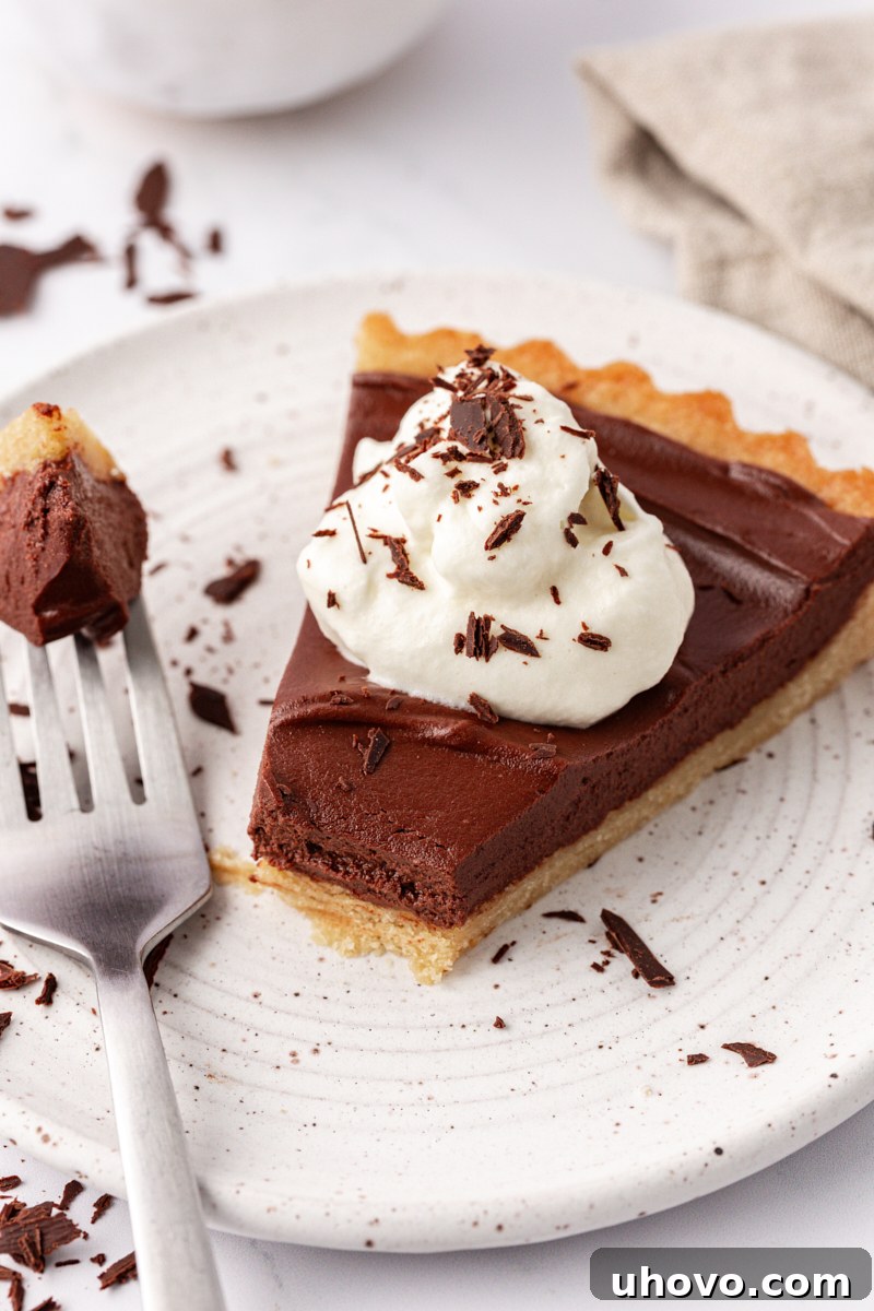 A delectable slice of chocolate mascarpone tart on a white plate, with a fork holding a bite, highlighting its rich texture.