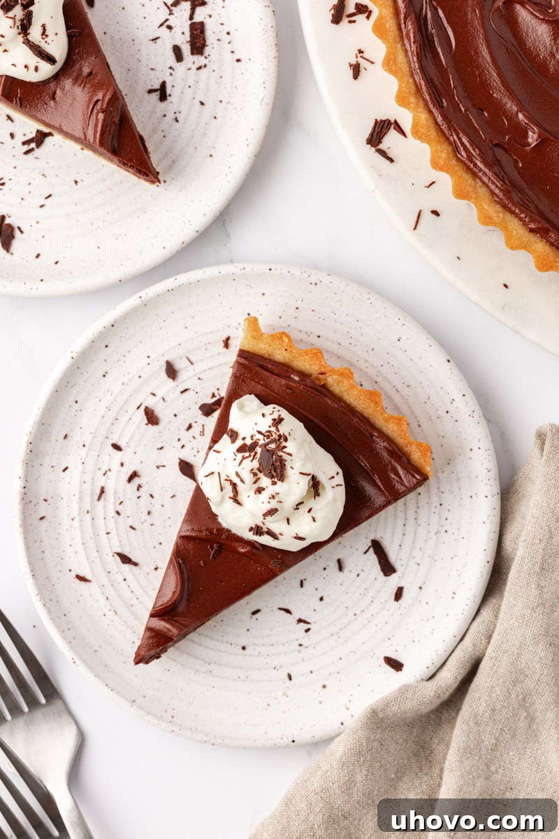 An overhead shot of a single, elegantly presented slice of chocolate mascarpone tart on a pristine white plate.