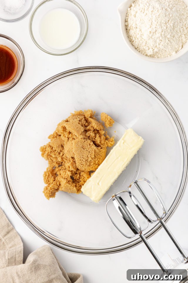 Creaming softened unsalted butter and light brown sugar together in a glass mixing bowl, a crucial first step for a tender tart crust.
