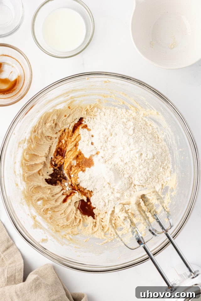 Adding all-purpose flour, a touch of vanilla extract, and salt to the creamed butter and sugar mixture for the tart crust.