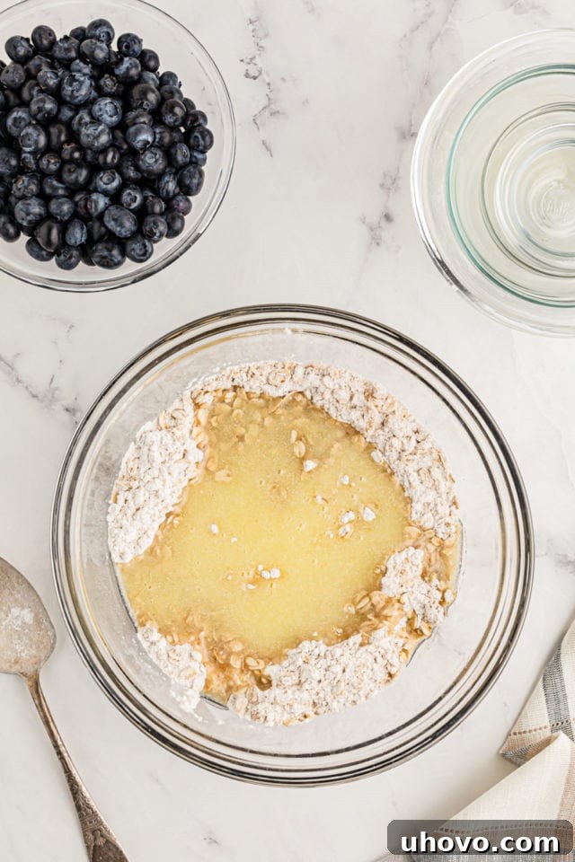Overhead view of melted butter added to dry ingredients for crust
