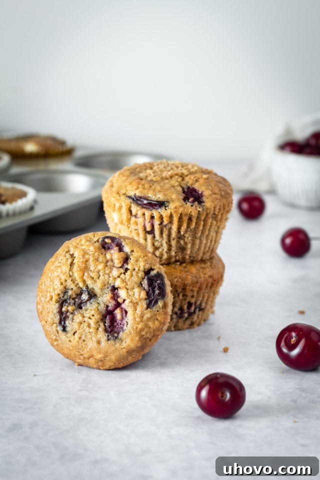 A stack of three Cherry Cheesecake Muffins on a grey surface, showing their enticing texture.