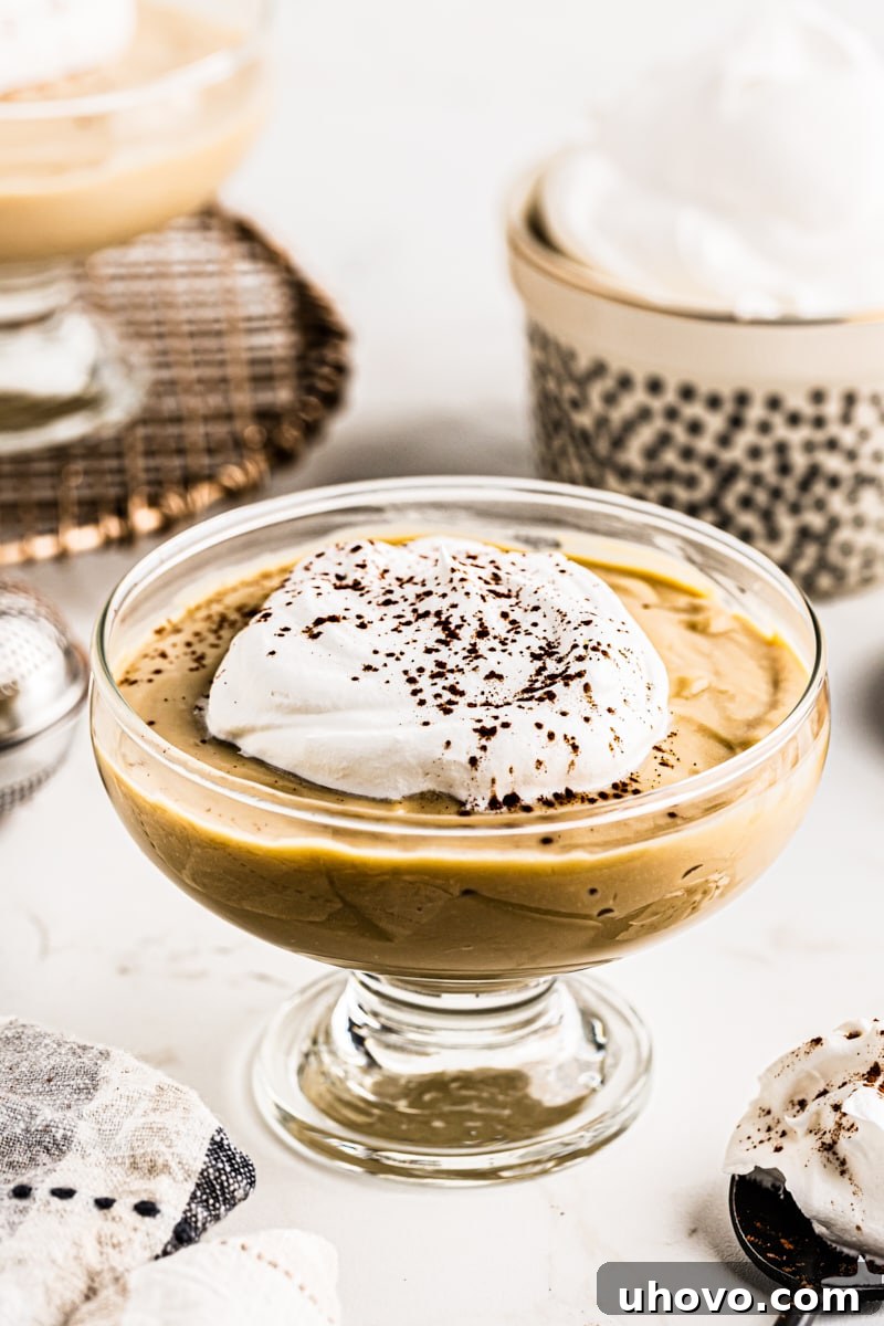 Classic Butterscotch Pudding topped with fresh whipped cream and a sprinkle of cocoa powder.