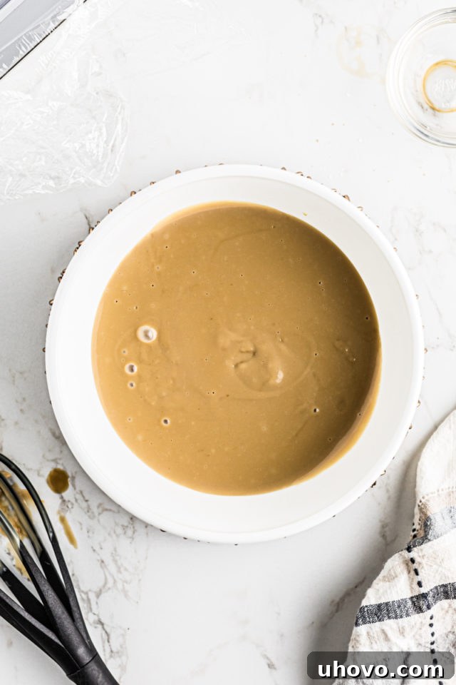 A generous serving of freshly made butterscotch pudding poured into a clean bowl, showcasing its rich color and smooth texture.