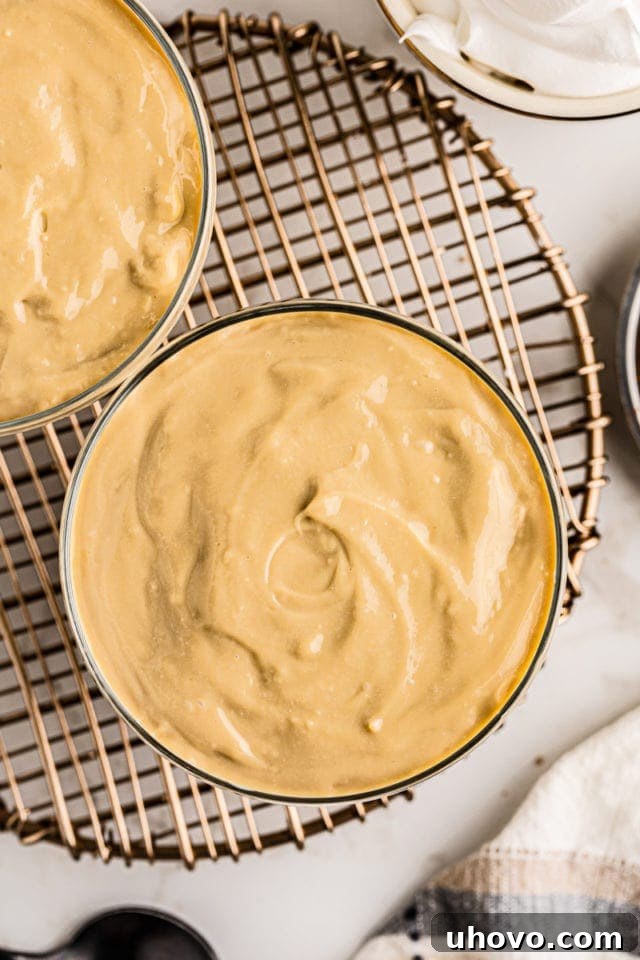 Multiple individual cups of smooth, golden butterscotch pudding, perfectly portioned and ready for serving or topping.