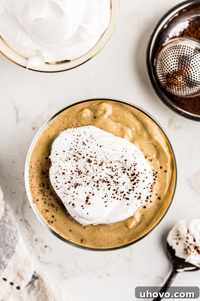 An inviting overhead shot of smooth butterscotch pudding, generously crowned with fluffy whipped cream, ready to be enjoyed.