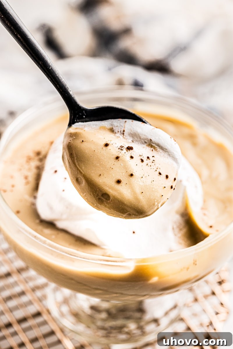 A spoonful of creamy butterscotch pudding lifted from a cup, showcasing its rich texture and tempting appeal.