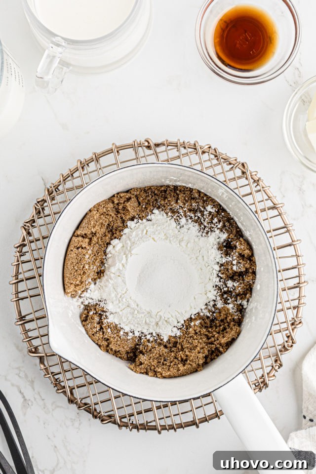 Dry ingredients for butterscotch pudding, including brown sugar, cornstarch, and salt, resting in a saucepan before whisking.