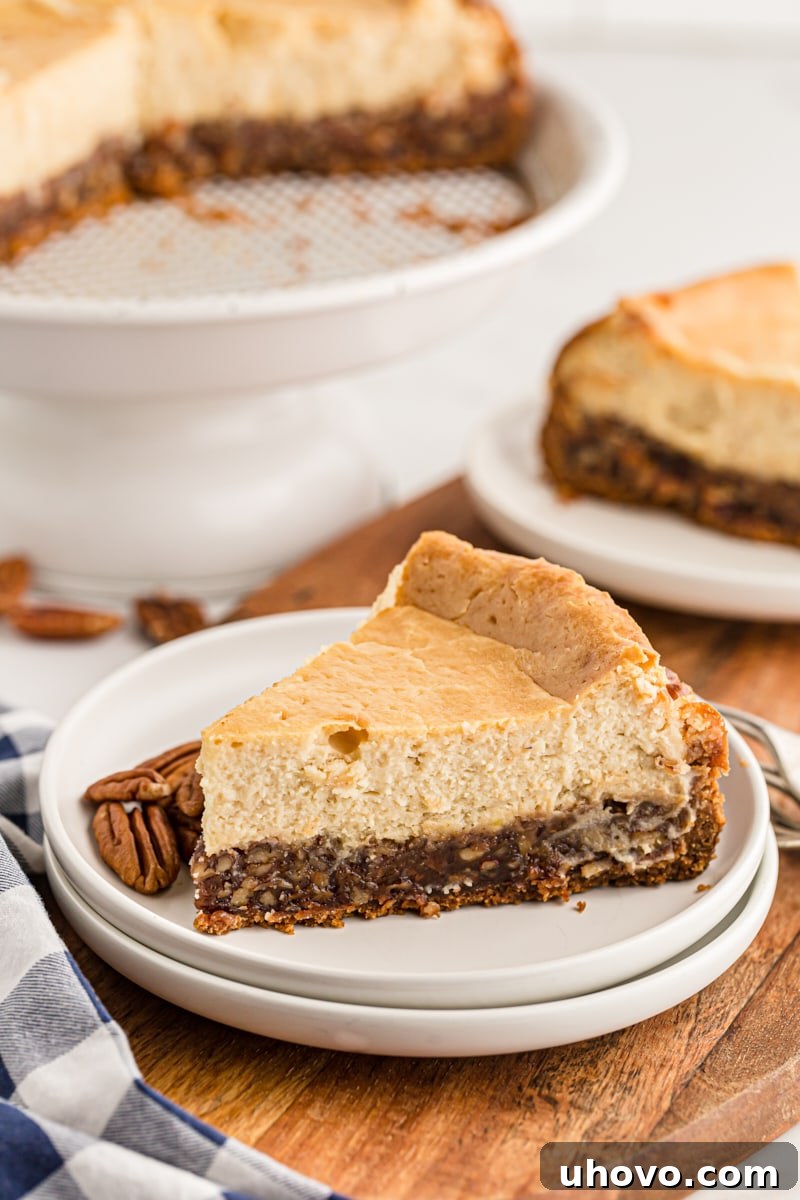 A perfectly sliced Pecan Pie Cheesecake, showcasing its distinct layers of crunchy pecan filling and creamy cheesecake, ready to be enjoyed.