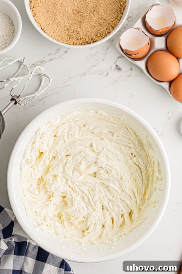 Beating softened cream cheese in a stand mixer until it becomes light, fluffy, and completely creamy.