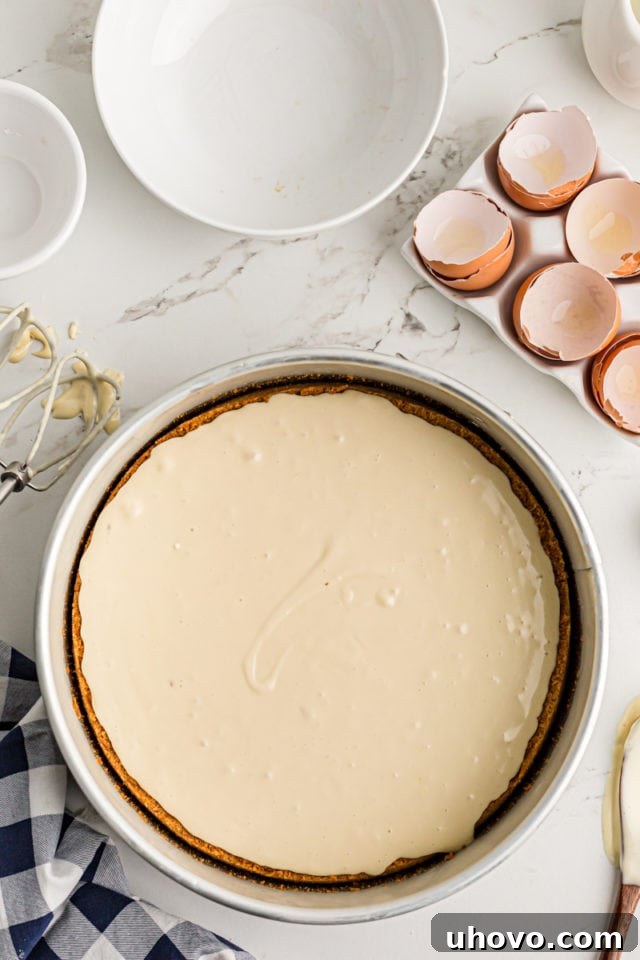 Pouring the smooth cheesecake batter gently over the set pecan filling in the springform pan, creating the final layer.
