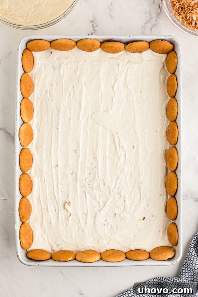 Overhead view of cream cheese layer in baking dish after adding vanilla wafers