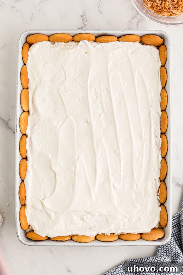 Overhead view of coconut cream pie bars in baking dish before adding toasted coconut