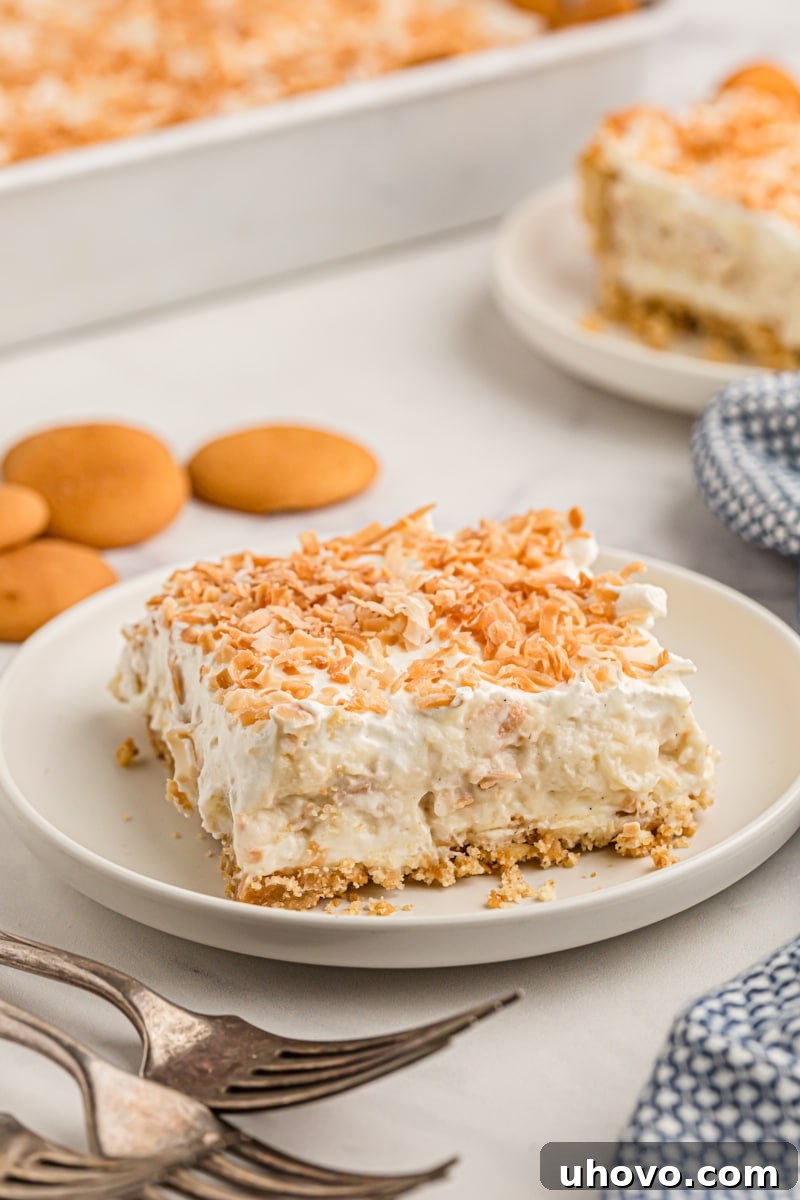 Coconut cream pie bar on plate with toasted coconut on top