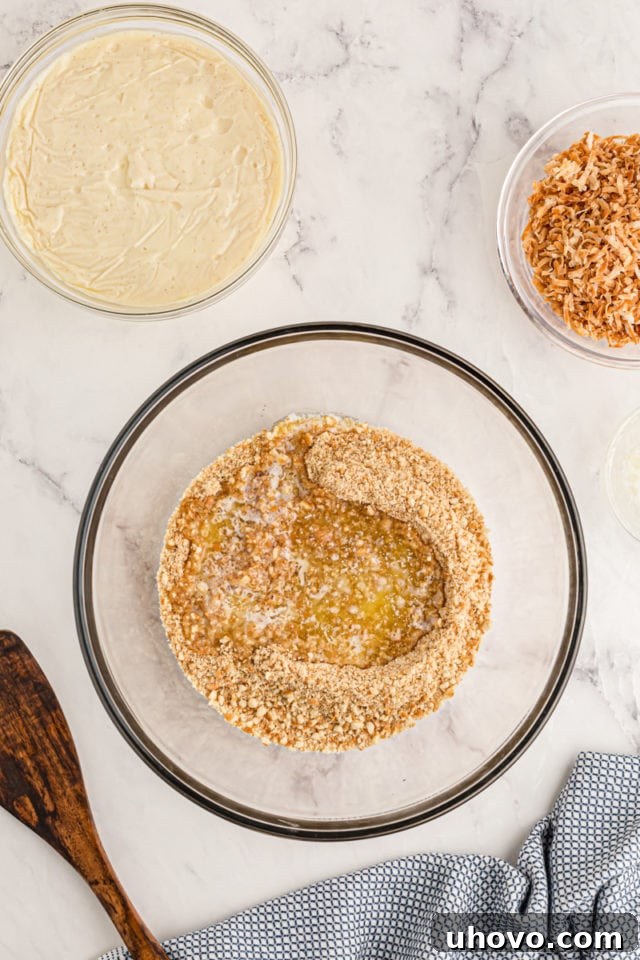 Overhead view of butter added to crushed vanilla wafers in bowl