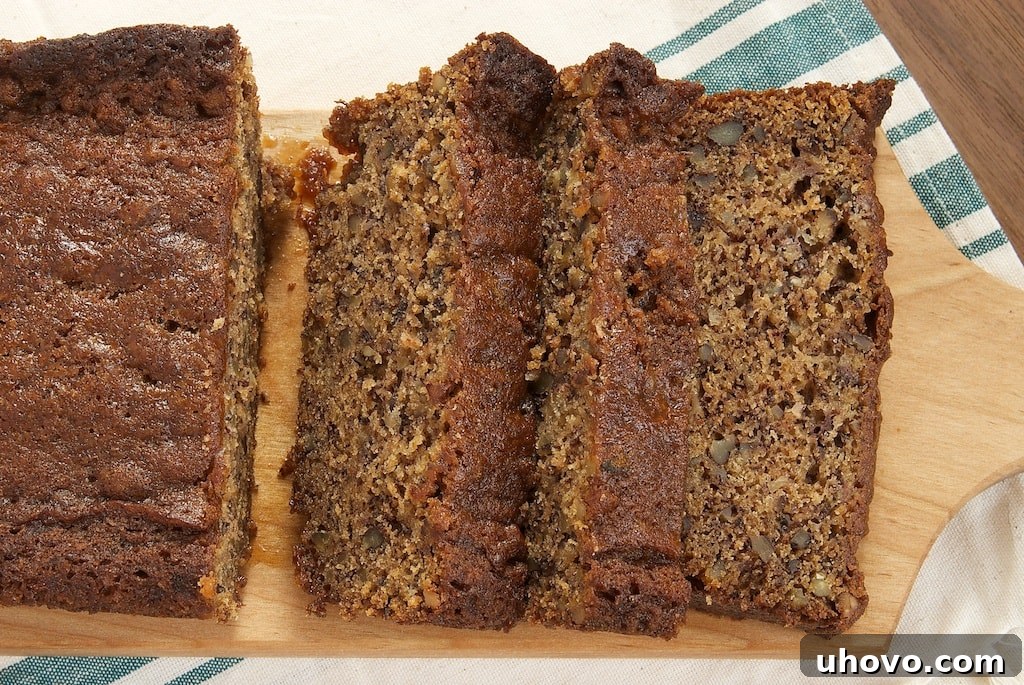 An inviting overhead shot of a freshly baked loaf of Chai Caramel Banana Bread, still warm, resting on a rustic wooden board. The beautiful, dark swirl of chai caramel is visible across the golden-brown surface, hinting at the rich flavors within.