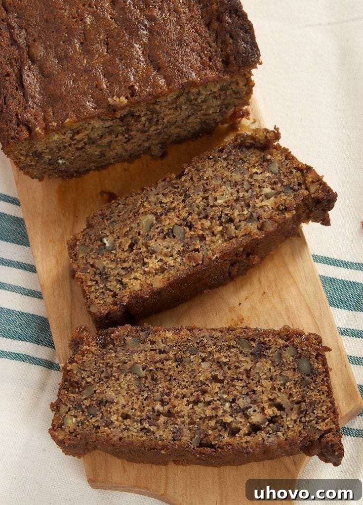 A perfectly sliced loaf of Chai Caramel Banana Bread on a wooden board, highlighting its moist texture and delightful caramel swirls.