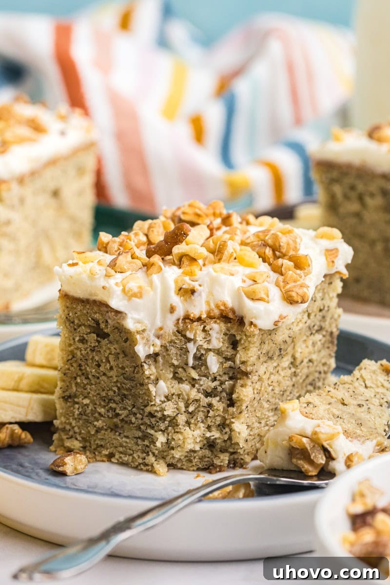 A charming close-up of a slice of banana cake with cream cheese frosting on a plate, with a bite expertly taken on a fork, highlighting its moist texture.