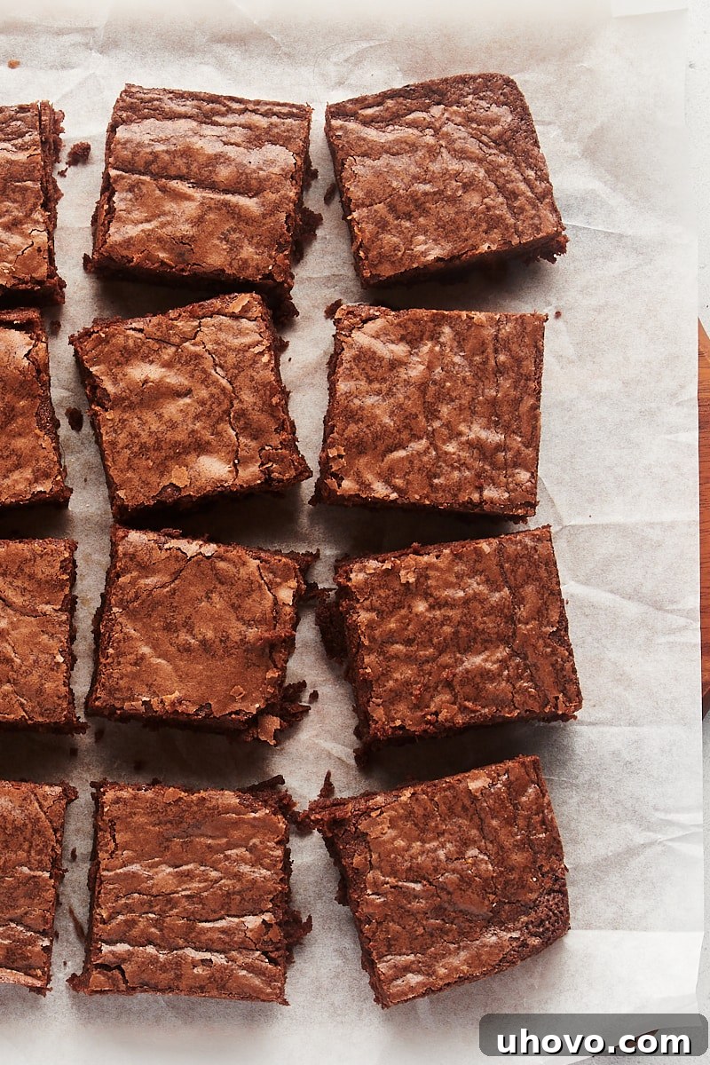 Overhead view of perfectly cut fudgy brownies arranged in neat squares on a cutting board.