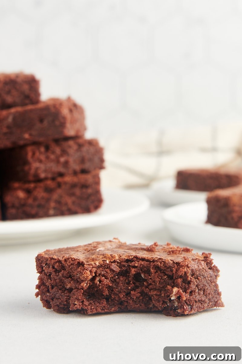 A fudgy brownie resting on a counter with a bite taken out, revealing its soft, rich interior.
