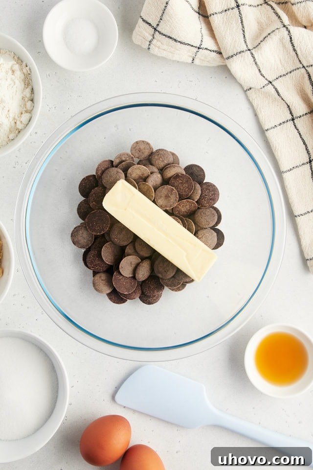 Overhead view of chocolate discs and butter in glass bowl, ready to be melted.