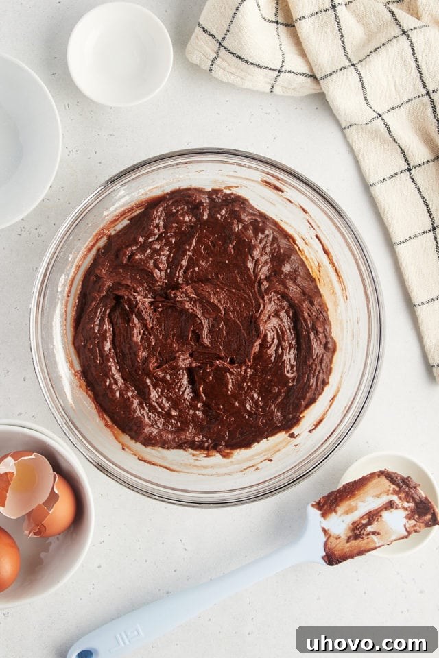 Overhead view of smooth, rich brownie batter in a glass mixing bowl, ready for baking.
