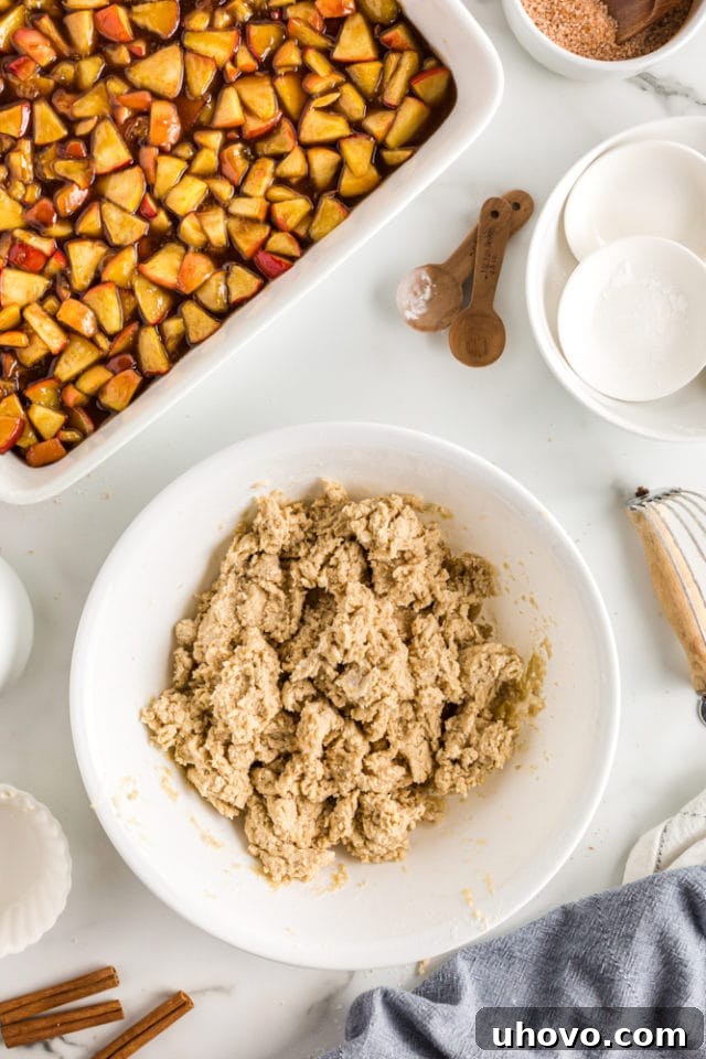 An overhead view of the finished, sticky topping mixture for the apple cobbler, nestled in a white mixing bowl, ready for assembly.